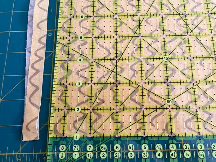 An Omnigrip ruler is used to square off the edge of yellow fabric.