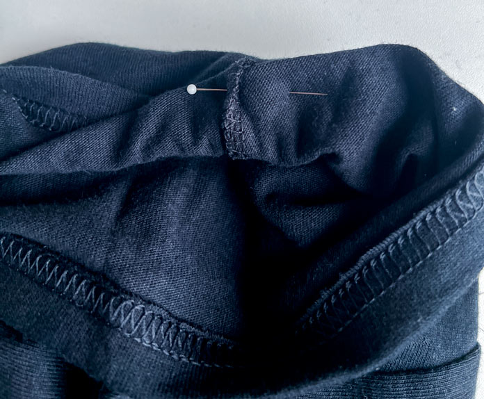 T-shirt sleeve prepared for embroidery, pinned flat and aligned at the underarm seam using a glass head pin to keep it secure 