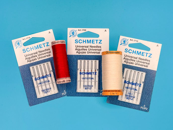 Multiple packages of different SCHMETZ Universal sewing machine needles and sizes with two spools of Gütermann Threads.