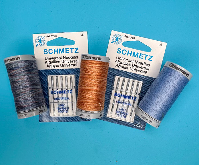 Multiple packages of different SCHMETZ Universal sewing machine needles and sizes with three spools of Gütermann Threads.
