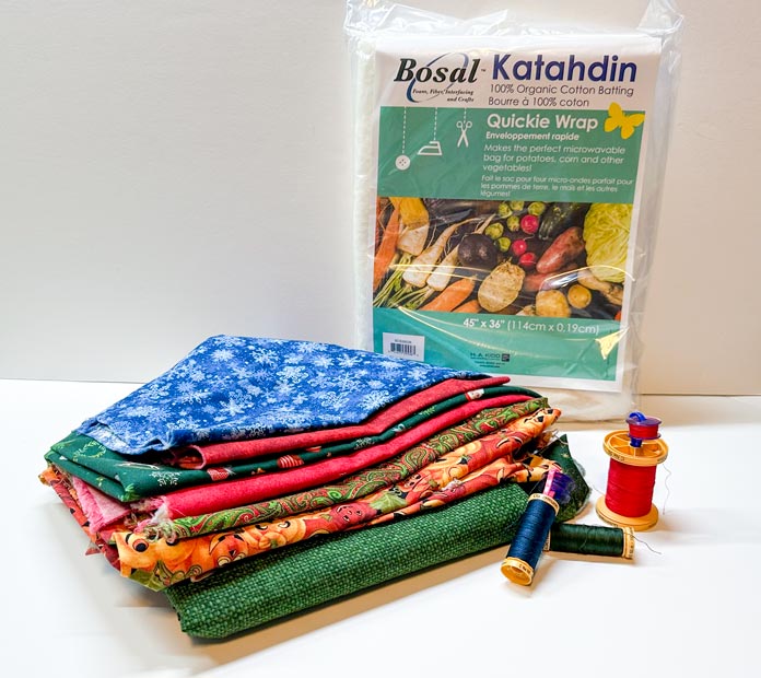 Green and pumpkin print fabric, 100% cotton fabrics cut into (1 each), 16” x 18” rectangles and (2) 16” x 18” rectangles of Bosal Katahdin Quickie Wrap (package shown), with a spool of 100% cotton green sewing thread.