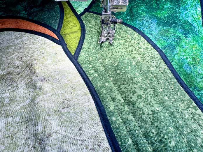 A section of the quilt is being quilted with parallel lines.