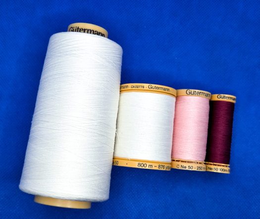 Four spools of thread on a blue background