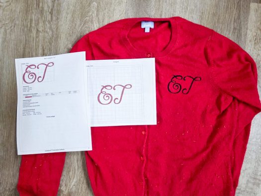 A red sweater with black stitching and two pieces of white paper