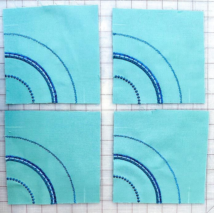 4 identical squares of light green fabric with ¼ circles of stitching.