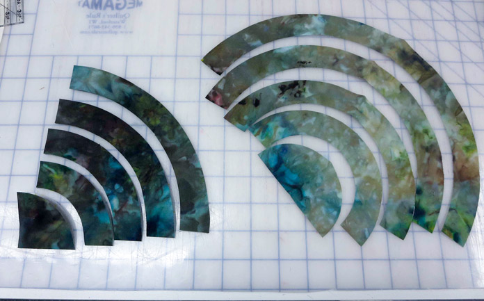 Folded ice-dyed fabric arcs on the left and finished fabric arcs cut with the OmniArc Circle Cutter ruler on the right