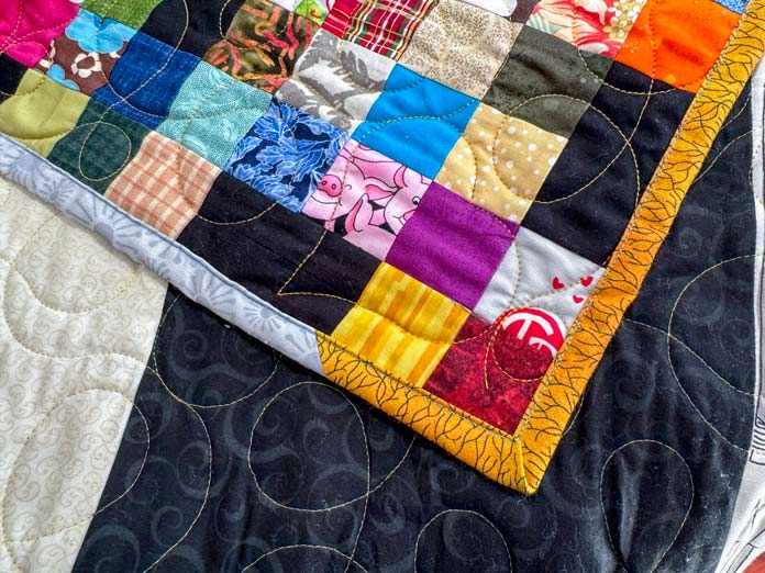 The corner of a quilt shows the binding made with two different fabrics.
