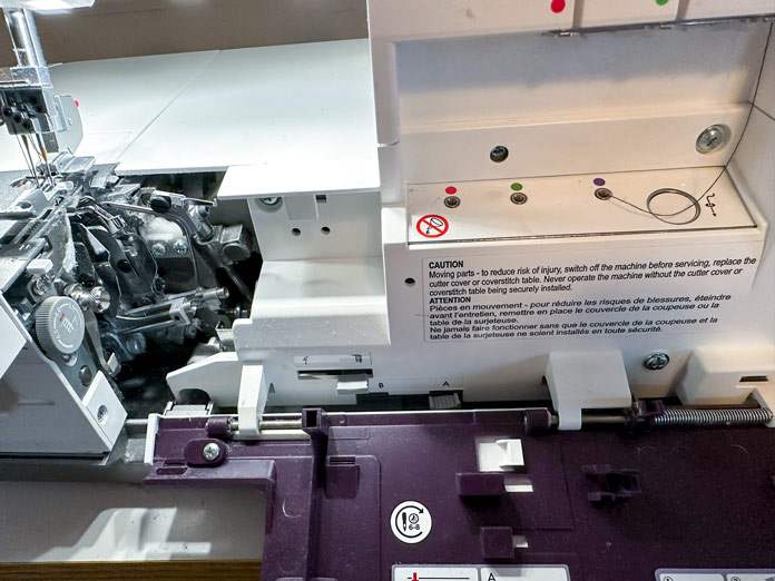 A purple and white serger open to show the threading paths used in a coverstitch; PFAFF admire air 7000 