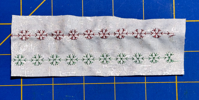 A sample of decorative stitched snowflakes with and without stabilizer sits on a blue cutting mat. The red portion that doesn’t have a stabilizer is not as smooth as the green portion that does. Gütermann Dekor Metallic Thread 200m – Gold, Gütermann Dekor Metallic Thread 200m - Col. 41, Gütermann Dekor Metallic Thread 200m – Red, Gütermann Dekor Metallic Thread 200m - Christmas Green, Gütermann Dekor Metallic Thread 200m - Col. 1005, Gütermann Denim Thread 100m – Black, UNIQUE Baby Rick Rack 3mm x 3.7m – Scarlet, UNIQUE Medium Rick Rack 6mm x 2.3m - Emerald Green, UNIQUE Jumbo Rick Rack 10mm x 2.3m - Metallic Gold, SCHMETZ #1743 Metallic Needles Carded - 80/12 - 5 count, SCHMETZ #1752 Metallic Needles Carded - 90/14 - 5 count, LDH 8½“ Craft Scissors – Purple, HeatnBond Lite Iron-On Adhesive - 43cm x 30m (17″ x 32 ¾yds) bolt, HeatnBond Stitch n Sew Tear-Away Stabilizer - 50.8cm x 22.8m (20″ x 25yds), oliso M3Pro Project Iron – Coral, OLFA 45mm RTY-2/DX/MAG Ergonomic Rotary Cutter – Magenta, UNIQUE Quilting Wool Pressing Mat - 18″ x 24″ - Grey