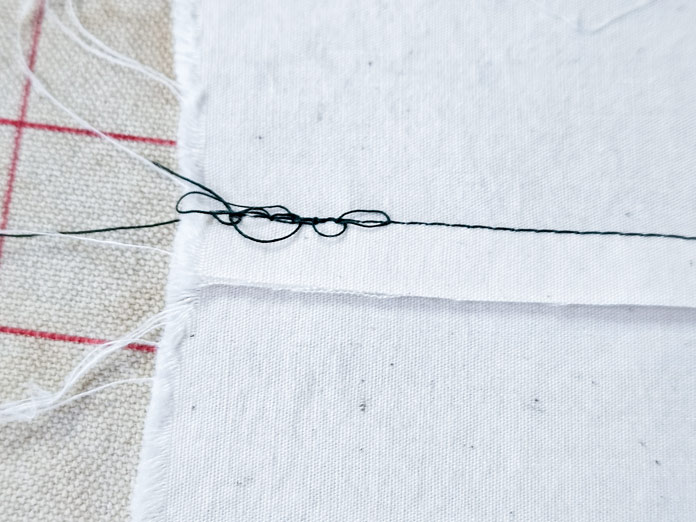A nest of dark thread on cream fabric