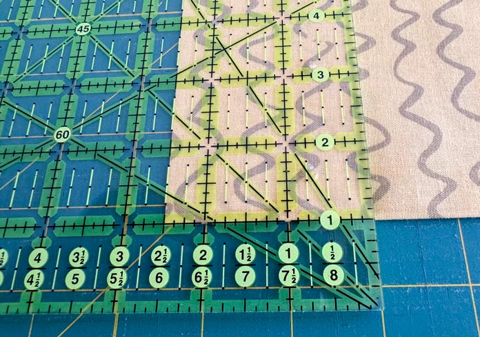 An Omnigrip ruler is used to cut 2½” strips from the yellow fabric.