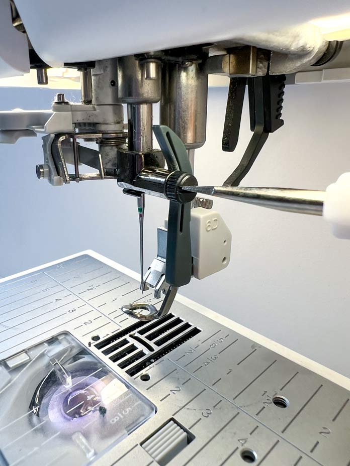 The Dynamic Spring Foot serves multiple purposes, catering to embroidery, free-motion sewing, and quilting needs. Its design offers an unobstructed view, ideal for executing stippling or following intricate fabric designs. Process of changing machine needle with a PFAFF mini machine screwdriver