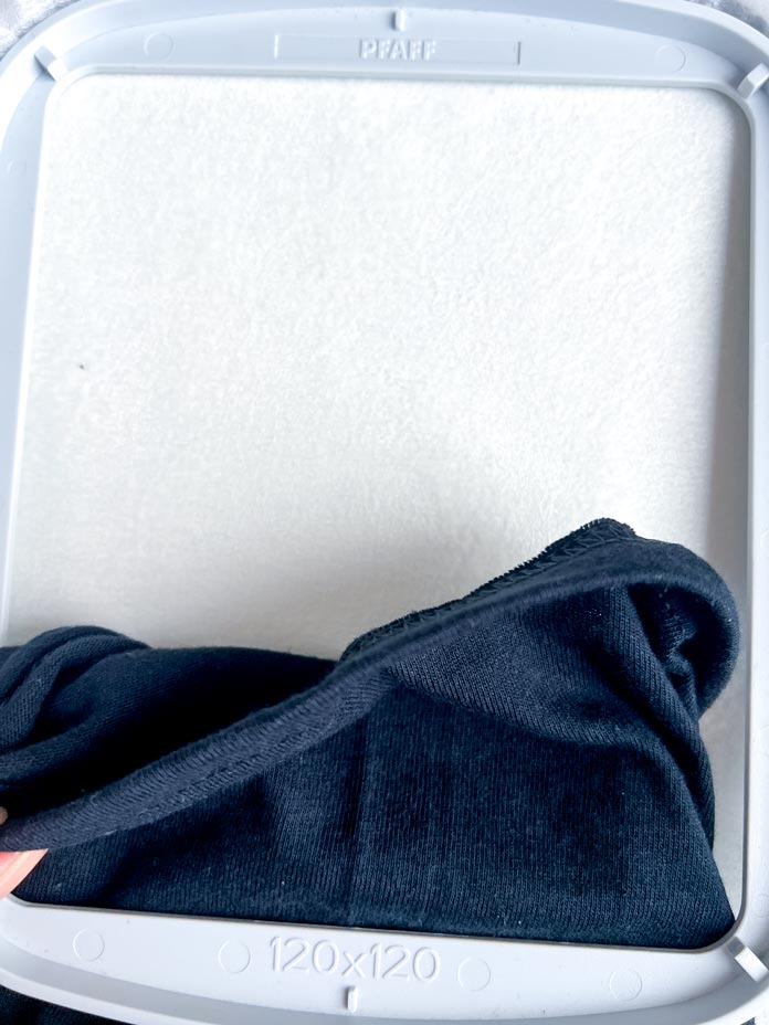 Process of hooping the T-shirt sleeve in PFAFF creative 120 Square Hoop (120 x 120 mm). Sleeve armpit seam is carefully matched and secured with a glass head pin, ready for centering in the hoop.