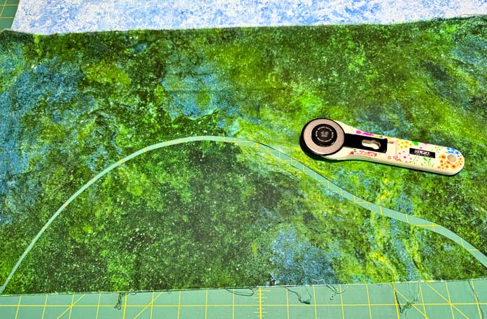 Using an OLFA 45mm rotary cutter to cut a green piece of fabric.