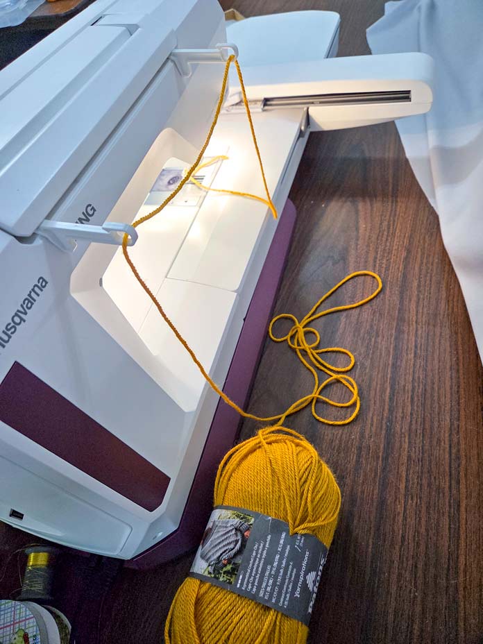 Skein of gold yarn beside a white sewing machine