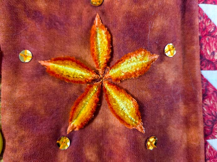 Orange and yellow stitching on brown fabricA Husqvarna VIKING Designer Topaz 65 Thread Velvet sample with two high contrast threads