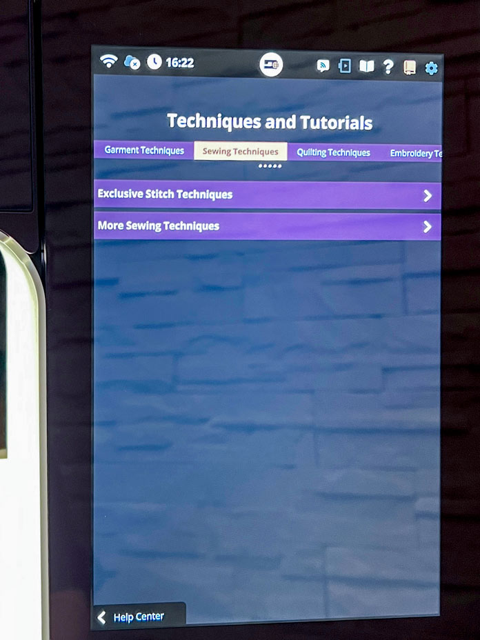 Touchscreen interface of the PFAFF creative icon 2 showing the "Techniques and Tutorials" section under "Sewing Techniques." Two menu options are visible: "Exclusive Stitch Techniques" and "More Sewing Techniques." The navigation tabs at the top include Garment Techniques, Sewing Techniques (highlighted), Quilting Techniques, and Embroidery Techniques.