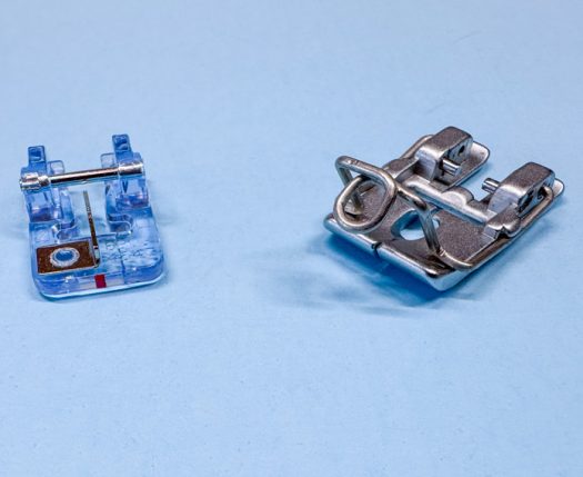 A purplish-blue plastic foot on the left with an open tunnel down the center and a metal wedge in the center of the tunnel. The metal foot on the right has a metal wire circle out in front to guide the yarn, a hole in the foot and a tunnel underneath, all to position the yarn, (or other soft cord) in the center of the foot to be couched down onto the fabric.