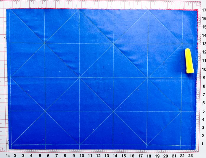 A diagonal line is drawn through each 4” x 4” square on the blue fabric. Clover Chaco Liners, Clover Quilting Pins, Clover 45mm Rotary Cutter, Gütermann 100% Cotton Thread, Gütermann Sew-All Polyester Thread