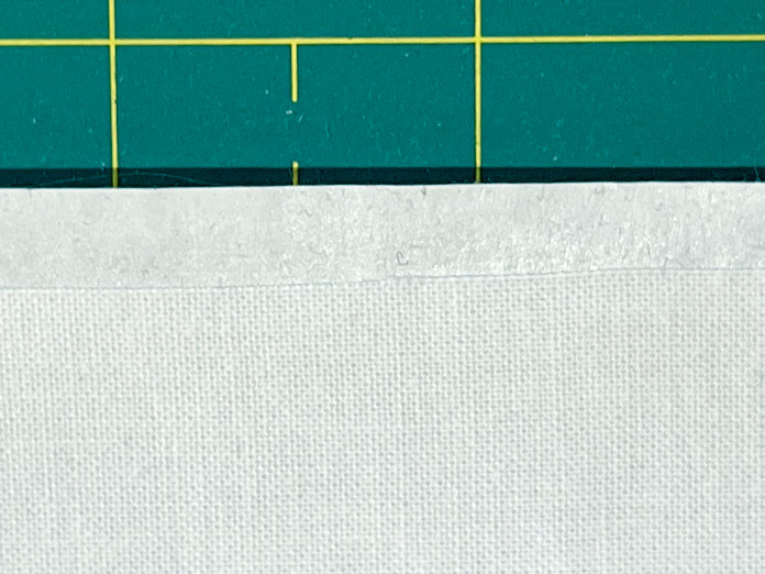 Freezer paper is pressed to fabric leaving a ¼” space at bottom of paper; Sew Easy Freezer Paper for Quilting and Applique - 12.1m x 38.1cm (13.2yd x 15″), OLFA Square Rotating Cutting Mat
