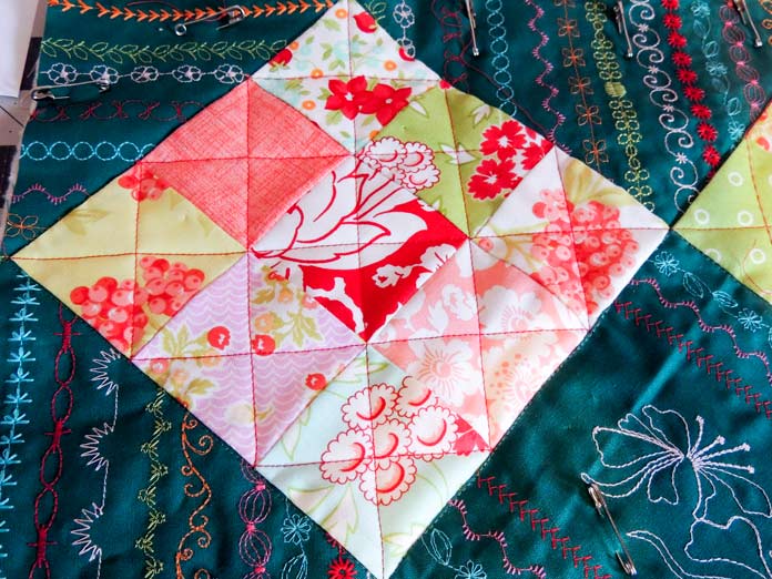A close-up of the machine quilting on a nine-patch block surrounded by the green stitched background fabric; part of the cushion cover.