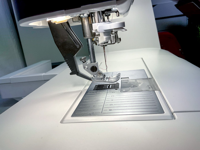 A side view of the PFAFF creative icon 2 sewing machine showing the needle threaded, presser foot and the lower feed dogs engaged