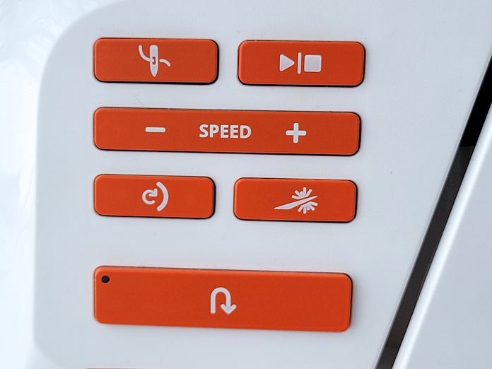 Six orange buttons on a white sewing machine; Husqvarna Viking DESIGNER EPIC 2