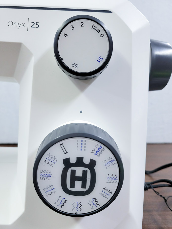 Two stitch dials on a white sewing machine; the Husqvarna VIKING ONYX 25