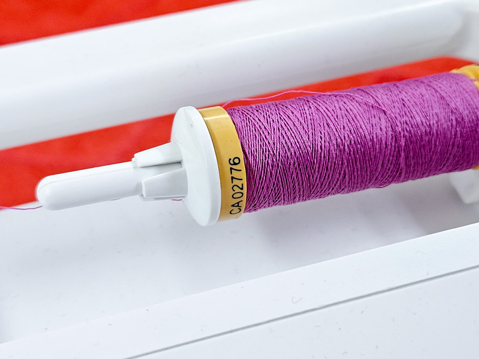 A spool of pink thread on a white sewing machine; making a project bag using Güterman Thread and the Husqvarna VIKING ONYX 25
