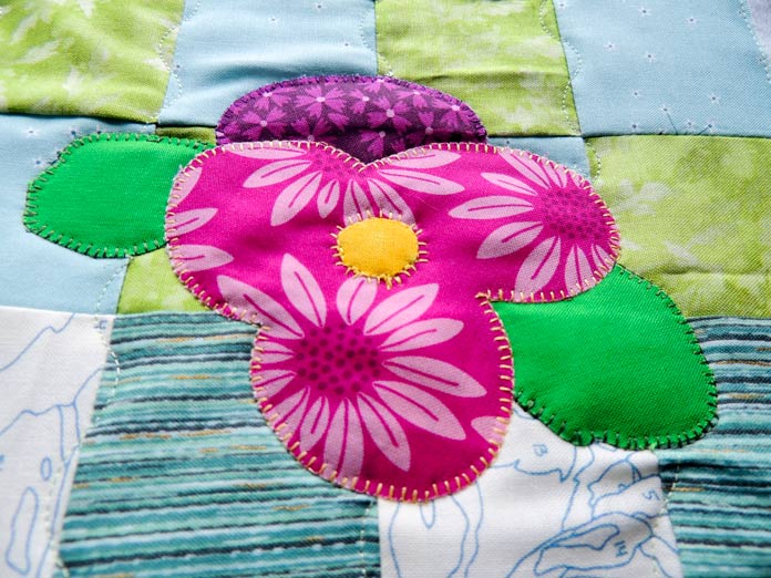 Closeup of blanket stitching in different colored threads on applique fabrics 