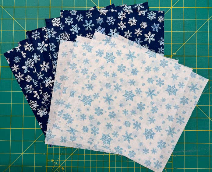 Four white snowflake fabrics on five dark blue snowflake fabrics.