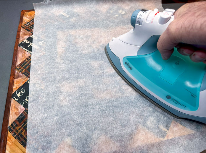 The quilt is covered with parchment paper as it’s being pressed to set the get.