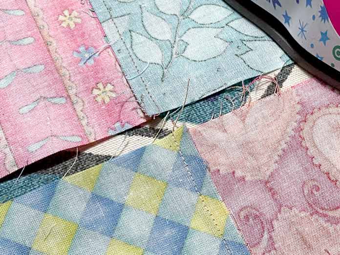 The back of four quilt blocks is shown so that the seams are visible. The seams have been pressed in opposite directions.