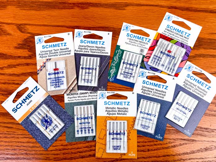 Multiple packages of different sewing machine needles and sizes.