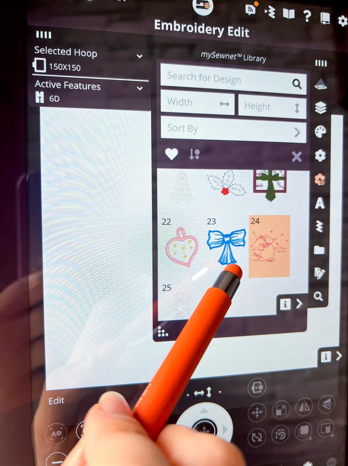 A purple model of the PFAFF creative icon 2 with Embroidery Edit mode and with mySewnet Library pop-up window with embroidery design options. A stylus touching the PFAFF creative icon 2 sewing machine 10.1-inch capacitive touch screen to open the embroidery design#24 