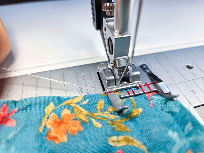 A metal presser foot on blue fabric