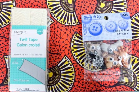 An orange fabric with yellow and brown fans, and a pack of animal buttons