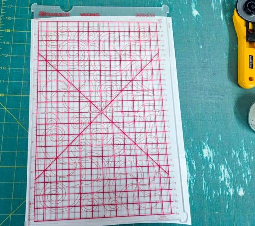 A plastic grid with red lines on a green cutting mat