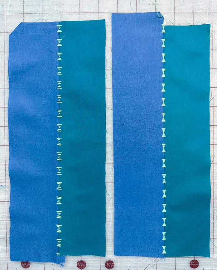2 blue and green pieces of fabric 3” x 12” seamed using a Floating Decorative Stitch in light green embroidery thread. Only the decorative satin stitch shows, the connector stitches in the seam are hidden.