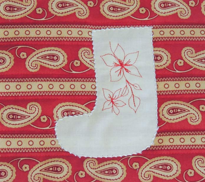 Large red floral stitches on a cream-colored stocking appliqued to red paisley-patterned fabric