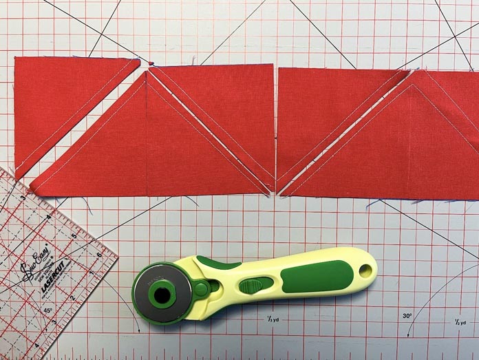 The sewn paired fabric strips are cut along all drawn lines to create HSTs. Clover Chaco Liner, Clover Quilting Pins, Clover Rotary Cutter