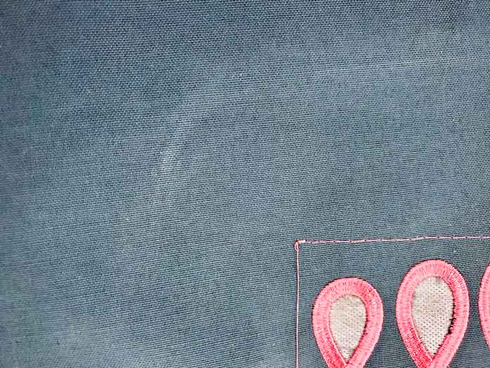 A faint white mark on a piece of green fabric. Husqvarna Viking Designer Sapphire 85 sewing and embroidery machine, Inspira Cut-A-Way Stabilizer, Inspira Embroidery Cutwork Needles, Odif 505 Temporary Quilt Basting Adhesive Fabric Spray, Inspira EZ Snip Curved Scissors, Inspira Aqua Magic Stabilizer