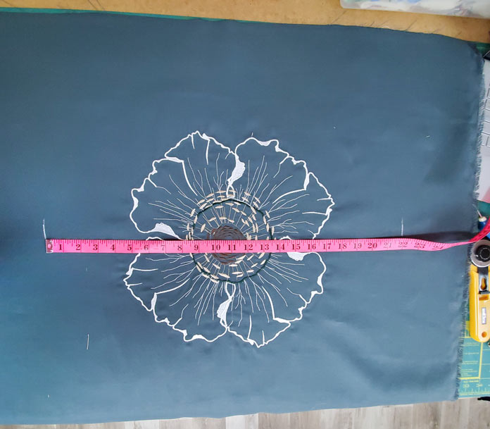 A pink quilting tape measure on a white embroidery flower on a green fabric, Husqvarna Viking Designer Sapphire 85, Inspira EZ Snip Curved Scissors