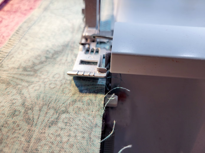 A strip of fabric under the presser foot of a serger