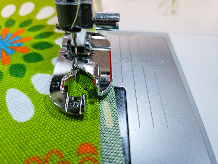 A metal presser foot on green fabric; Gütermann Nostalgia Box - 50wt Cotton Thread 100m - 48 Shades, Gütermann Nostalgia Box, Flat Felled Foot 9mm, Husqvarna VIKING Opal 690Q, free sewing pattern, outdoor accessories, outdoor cushions