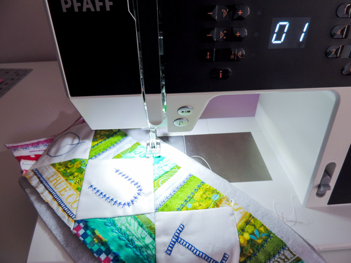Quilting the wall quilt on the passport 2.0 with presser foot lined up at letter u block