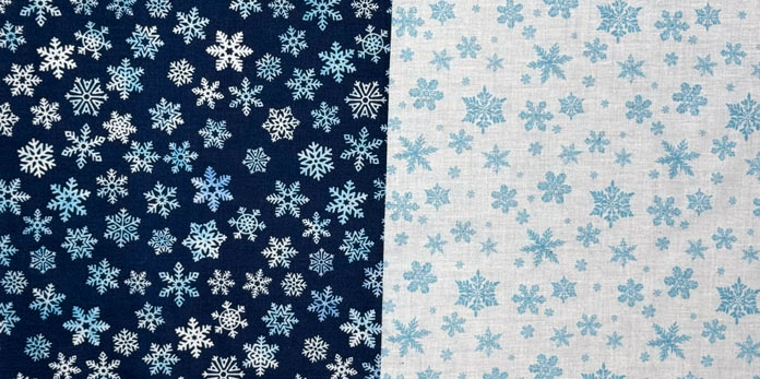 Two squares, one dark blue and one white snowflake fabric are sewn to each other.