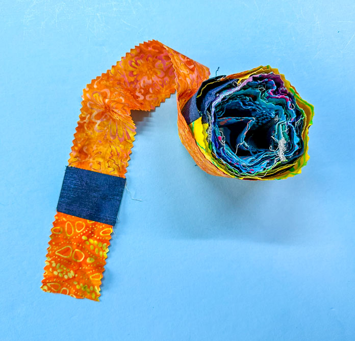A roll of strips of (½ selvedge to selvedge) from my rainbow bright jelly roll, with navy mottled squares in between. So, strip to square, strip to square