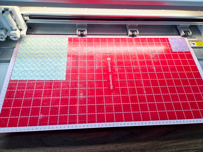 A red cutting mat with two pieces of fabric