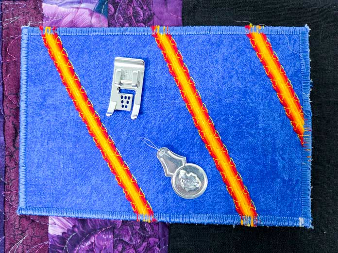 A blue fabric postcard with orange and yellow stripes